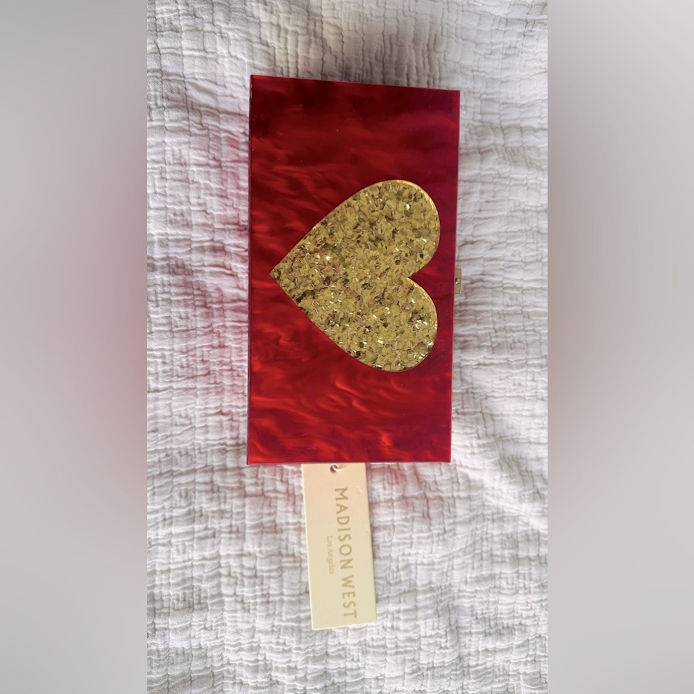 Madison West clutch in a red marbled design with a sparkling gold heart accent.